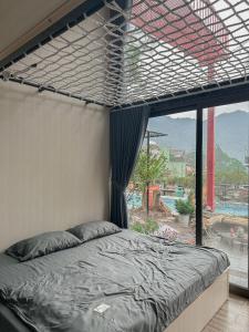 1 cama en un dormitorio con ventana grande en Bách Xanh House. Triangle Bungalow, en Tam Ðảo