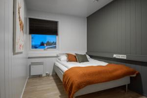 a bedroom with a bed with an orange blanket and a window at Skillevollen Motell in Mo i Rana