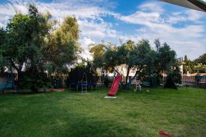 un parco giochi con scivolo rosso in un cortile di The Big Cypress Apartments ad Apólpaina