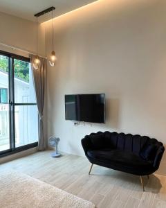 a black leather couch in a living room with a flat screen tv at Lucid Dream清醒夢民宿 in Yilan City