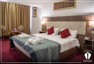 Abu Sanaa Hotel في السليمانية: غرفة فندق عليها سرير وفوط