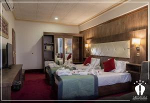 una camera d'albergo con tre letti e una televisione di Abu Sanaa Hotel a As Sulaymānīyah
