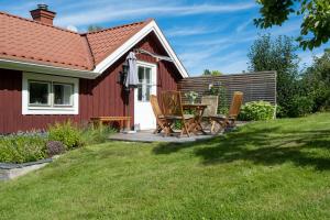 a red house with a table and chairs on a deck at Seaside Cottage Nr 3, Saltvik Hudiksvall in Hudiksvall +5 photos