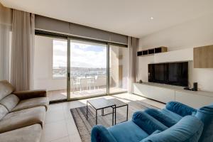 een woonkamer met een blauwe bank en een groot raam bij Luxe Apartment with Valletta and Harbour Views in Sliema