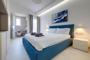een slaapkamer met een groot bed met een blauw hoofdeinde bij Luxe Apartment with Valletta and Harbour Views in Sliema