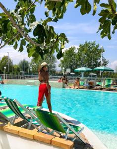 a young boy standing on a chaise lounge next to a swimming pool at Lianna Beach Resort in Marina di Montenero