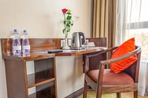 un escritorio de madera con un jarrón de flores. en Hotel Rio en Nairobi