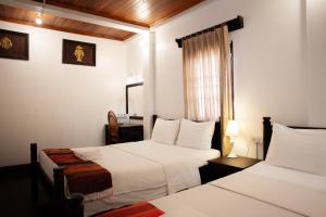 a hotel room with two beds and a window at Villa Senesouk Luang Prabang in Luang Prabang