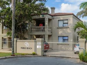 a house with a fence in front of it at Pebble Beach in Uvongo Beach