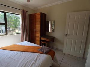 a bedroom with a bed with a dresser and a window at Pebble Beach in Uvongo Beach +22 photos