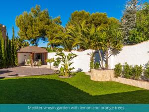 un patio con jardín con césped y naranjos en Villa Serenity - HMR Holidays, en Moraira