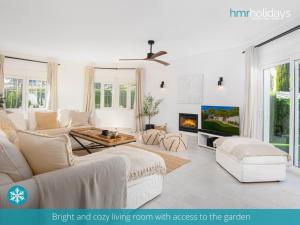 sala de estar con muebles blancos y TV en Villa Serenity - HMR Holidays, en Moraira