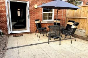 Una mesa y sillas con una sombrilla en un patio. en New! Peaceful 4 Bed home - Quiet and Cosy, en Kent