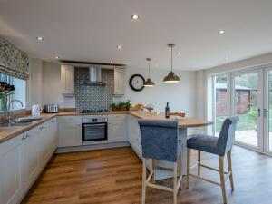 a kitchen with white cabinets and a wooden counter top at Wisteria House in Henstead