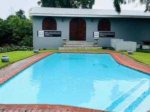 una grande piscina blu di fronte a una casa di The Midlands Hotel a Pietermaritzburg