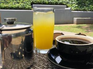 szklankę soku pomarańczowego i filiżankę kawy na stole w obiekcie The Midlands Hotel w mieście Pietermaritzburg