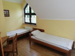 een kamer met 2 bedden, een tafel en een raam bij Muzeum Archeologiczne w Biskupinie - Dom Muzealnika in Biskupin