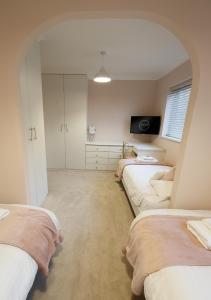 a bedroom with three beds and a television in it at The Masters by STAMP SA in Lytham St Annes