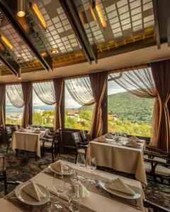 un restaurante con mesas, sillas y ventanas grandes en Hotel Belvedere, en Brasov