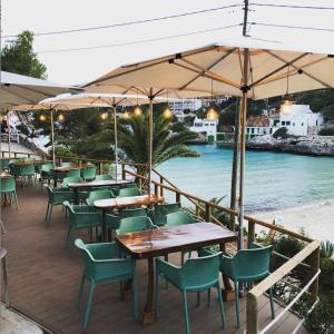 un restaurant avec des tables et des chaises et la plage dans l'établissement Hostal Playa, à Cala Santanyí