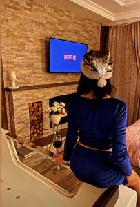 a woman sitting in front of a tv with a glass of wine at Spa Apartman URBAN Life ZAJEČAR in Zaječar +10 photos