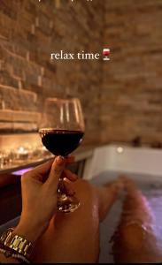 a woman holding a glass of wine in a bath tub at Spa Apartman URBAN Life ZAJEČAR in Zaječar