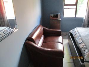 a brown leather couch in a room with a bed at PS GOOD TIME GUEST HOUSE in Klerksdorp