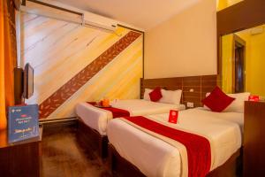 una camera d'albergo con due letti con accenti rossi di Hotel Snowland a Pokhara