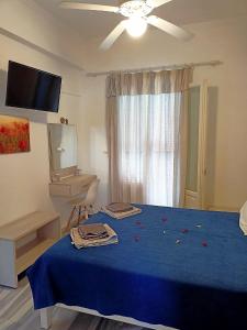 een slaapkamer met een blauw bed en een plafondventilator bij Marisa Rooms in Parikia