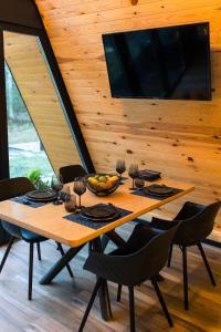 mesa de madera con sillas y TV en la pared en The Palo Cabins en Predeal