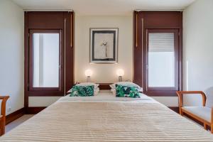 a bedroom with a large bed with two windows at Troia Seaside in Troia