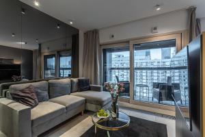 uma sala de estar com um sofá e uma grande janela em Mennica Residence Apartments by P&O Serviced Apartments em Varsóvia
