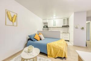 a bedroom with a blue bed and a kitchen at Charmant T2 proche de Disney in Noisy-le-Grand
