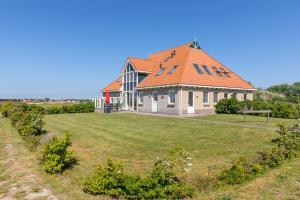 una casa con techo naranja en un campo de césped en Wadden Villa 12, en Hollum