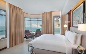 a hotel room with a bed and a view of the ocean at The Townhouses The Pearl in Doha