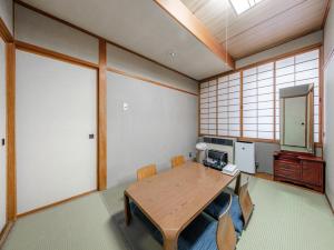 Zimmer mit einem Holztisch mit Stühlen und einem Spiegel in der Unterkunft Tabist THE GREEN OTARU in Otaru