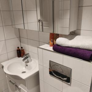 a white bathroom with a sink and a mirror at Nydelig leilighet, Free parking near sentrum in Bergen