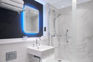 a white bathroom with a sink and a shower at Strand Palace in London