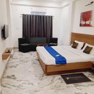 a bedroom with a bed and a chair and a couch at Hotel Nisha Nest, Bhopal in Bhopal