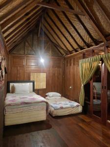 two beds in a room with wooden walls at Kayu81- Beautiful Pool Vila Ubud Mountain View 2BR in Bedahulu