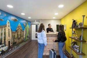 Um homem e duas mulheres ao balcão. em Bank Square Town House em Belfast