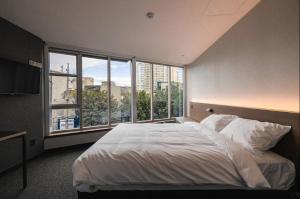 a bedroom with a large bed and a large window at Pillowsopher Hongdae in Seoul