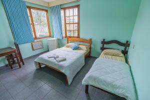 2 camas en una habitación con paredes y ventanas azules en Pousada Recanto de Itacuruçá, en Itacuruçá