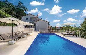 a swimming pool with chairs and umbrellas on a patio at Nice Home In Kastav With Wifi in Kastav