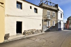 een oud wit gebouw met een deur en een straat bij Un gioiello in centro storico in Bari Sardo