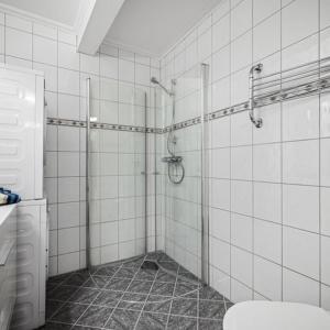 a white tiled bathroom with a shower and a toilet at Holmboe Apartment in Bergen