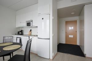 Il comprend une cuisine équipée d'une table et d'un réfrigérateur blanc. dans l'établissement New apartment, two bed room, free car park, à Turku