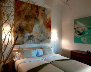 een slaapkamer met een bed met een schilderij aan de muur bij El Telar Arte y Naturaleza in Prádena