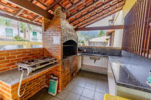 uma cozinha exterior com um forno de tijolos e um lavatório em Pousada Recanto de Itacuruçá em Itacuruçá
