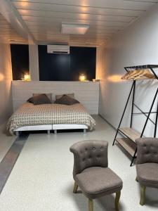 a bedroom with a bed and two chairs at Les Chambres de Campagne in Campagne